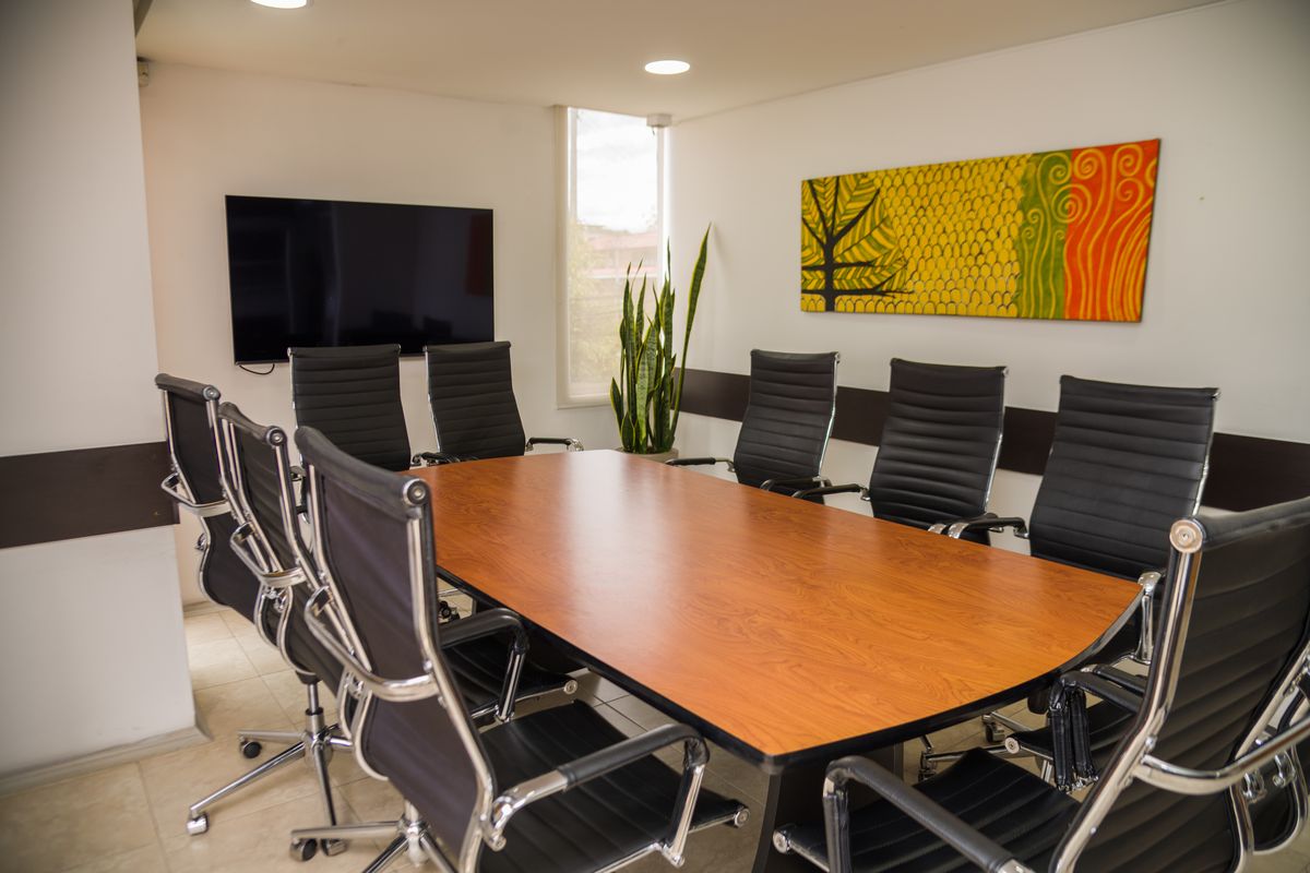 Sala de juntas con mesa de madera y sillas ejecutivas